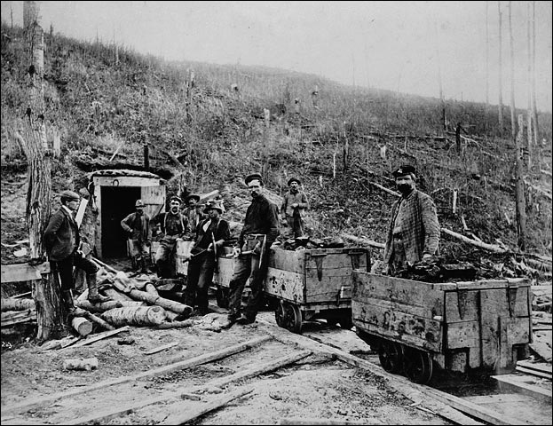 Mineurs et chariots de minerai à l'entrée d'une mine
