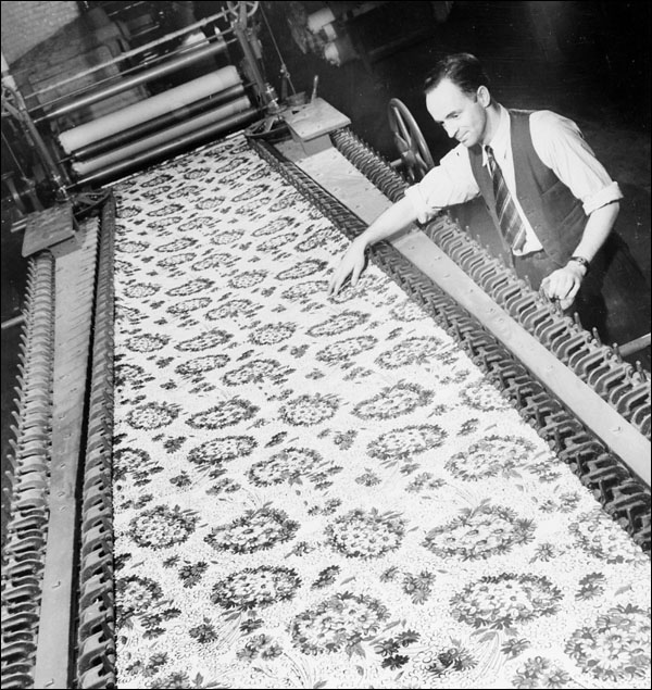 Homme portant une cravate essayant de saisir un coupon de tissu produit par une machine pour textiles