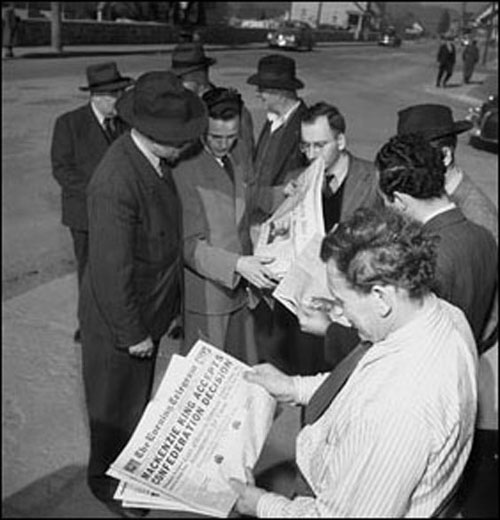 Citizens reading newspaper headlines concerning confederation with Canada, 