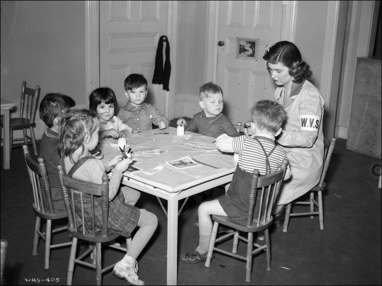 Women's Voluntary Service assistant helping children with pasting at day nursery in the Givens Street School, Toronto, Ontario, February 1943.