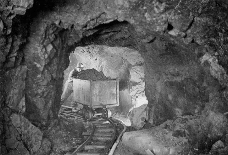 A miner hauling a car of silver radium ore, 340 feet below the surface, Eldorado Mine of Great Bear Lake, 1930